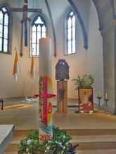 Das zweite Bild zeigt die Osterkerze von 2020 und im Hintergrund zwei Fahnen, den Tabernakel sowie eine Ikone mit dem auferstandenen Christus